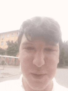 a close up of a young man 's face with a building in the background .