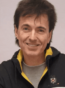 a man wearing a black jacket with a yellow collar that says nc polo club