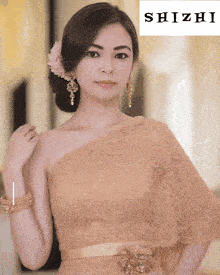 a woman with a flower in her hair is standing in front of a shizhi logo