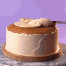 a cake is being frosted with white frosting on a wooden plate