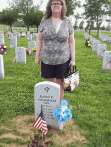 a woman stands in front of a grave of david f ingram