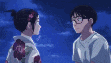 a boy and a girl are looking at each other while a fireworks display is going on in the background .