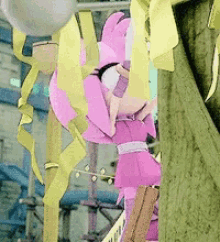 a pink stuffed animal is hanging from a tree with yellow ribbons