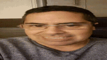 a close up of a man wearing glasses and a gray shirt making a funny face .