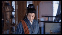 a man in a kimono is standing in a room with a sword on his shoulder .