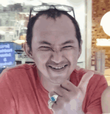 a man wearing a red shirt and a ring on his finger makes a funny face