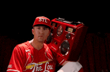 a man wearing a stl hat stands next to a boombox