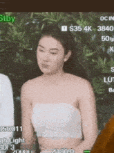 a woman in a white crop top is sitting in front of a computer monitor .
