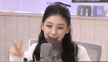 a young woman is sitting in front of a microphone .
