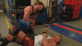 a man kneeling down next to a man laying on the floor with a shirt that says ohio