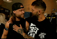 two men are hugging each other and one has a shirt that says street fighter on it