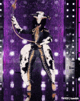 a woman in a cow costume is holding a whip on a stage