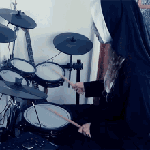 a woman in a nun costume is playing a drum set