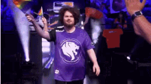 a man wearing a purple shirt with a white lion on it holds a flag