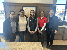 a group of people posing for a picture with one wearing a name tag