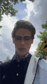 a young man wearing glasses is standing in front of a sign that says ' a few steps ahead '
