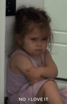 a little girl with her arms crossed and the words no i love it behind her