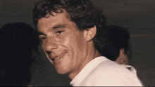 a man with curly hair is smiling in a dark room .