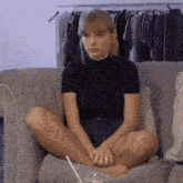 a woman is sitting on a couch with her legs crossed and a drink in her hand .