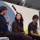 a man is holding a microphone while a woman sits in front of him