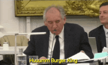 a man in a suit and tie is talking into a microphone and the words huuumm burger king are visible