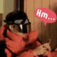 a man wearing a helmet and goggles is holding a cell phone and talking .