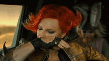 a woman with red hair is wearing gloves and covering her mouth