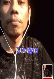 a man wearing ear buds and a shirt that says komeng on it