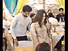 a man and a woman are standing next to each other in front of a crowd at a party .