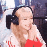 a woman wearing headphones and a red sweater is smiling while sitting in a chair .