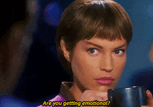 a woman holding a cup with the words are you getting emotional behind her