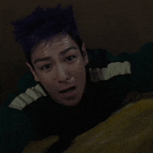 a man with purple hair is laying on his back with his mouth open