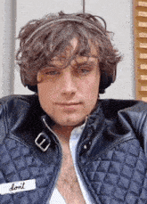 a young man wearing headphones and a leather jacket has a patch on his jacket that says " do n't "