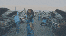 a group of people are dancing in a parking lot with their hoods up