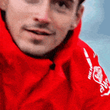 a close up of a man wearing a red jacket with the word five on it