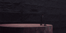 a man in a black coat stands on a large circular platform