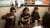a man wearing a shirt that says soul death is sitting at a table with others