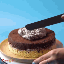 a person is spreading frosting on a cake with yum up written on the bottom of the cake