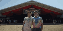 a man and a woman pose in front of a sign that says " the hangar "