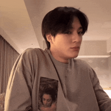 a young man wearing a gray shirt with a picture of a woman on it