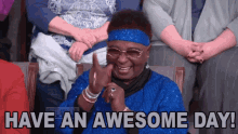 a woman in a blue dress and headband is sitting in a crowd and says have an awesome day .