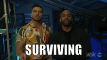 two men are standing next to each other and the word surviving is on the screen behind them