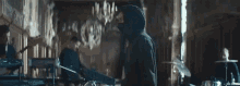 a man in a hooded jacket is playing a guitar in a band in a large room .