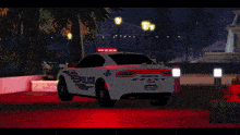 a white police car is parked in front of a building at night