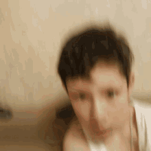 a blurry picture of a boy 's face with a white shirt on