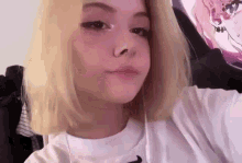 a girl with blonde hair and a nose ring is taking a selfie in front of a wall .