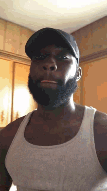 a man with a beard wearing a black hat and a tank top
