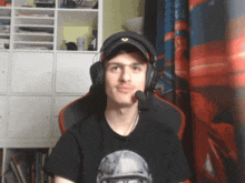 a man wearing a hat and headphones is sitting in front of a red curtain