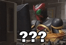 a man in a superhero costume is sitting in front of a computer screen with a question mark on it