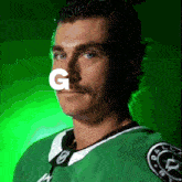 a man with a mustache is wearing a green jersey with the letter g on his nose
